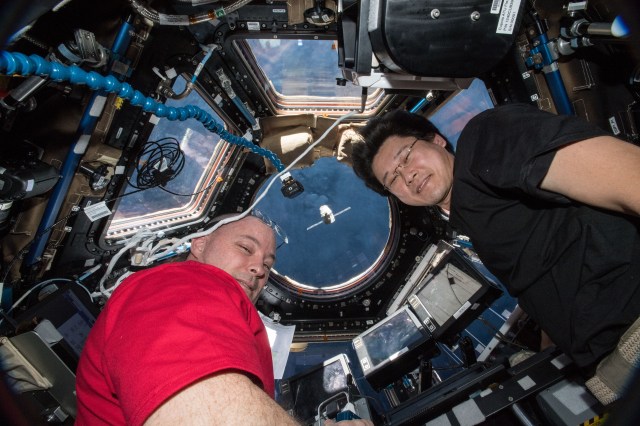 Astronauts Scott Tingle (left) and Norishige Kanai watch the SpaceX Dragon cargo craft arrive from inside the seven-windowed Cupola moments before capturing it with the Canadarm2 robotic arm.