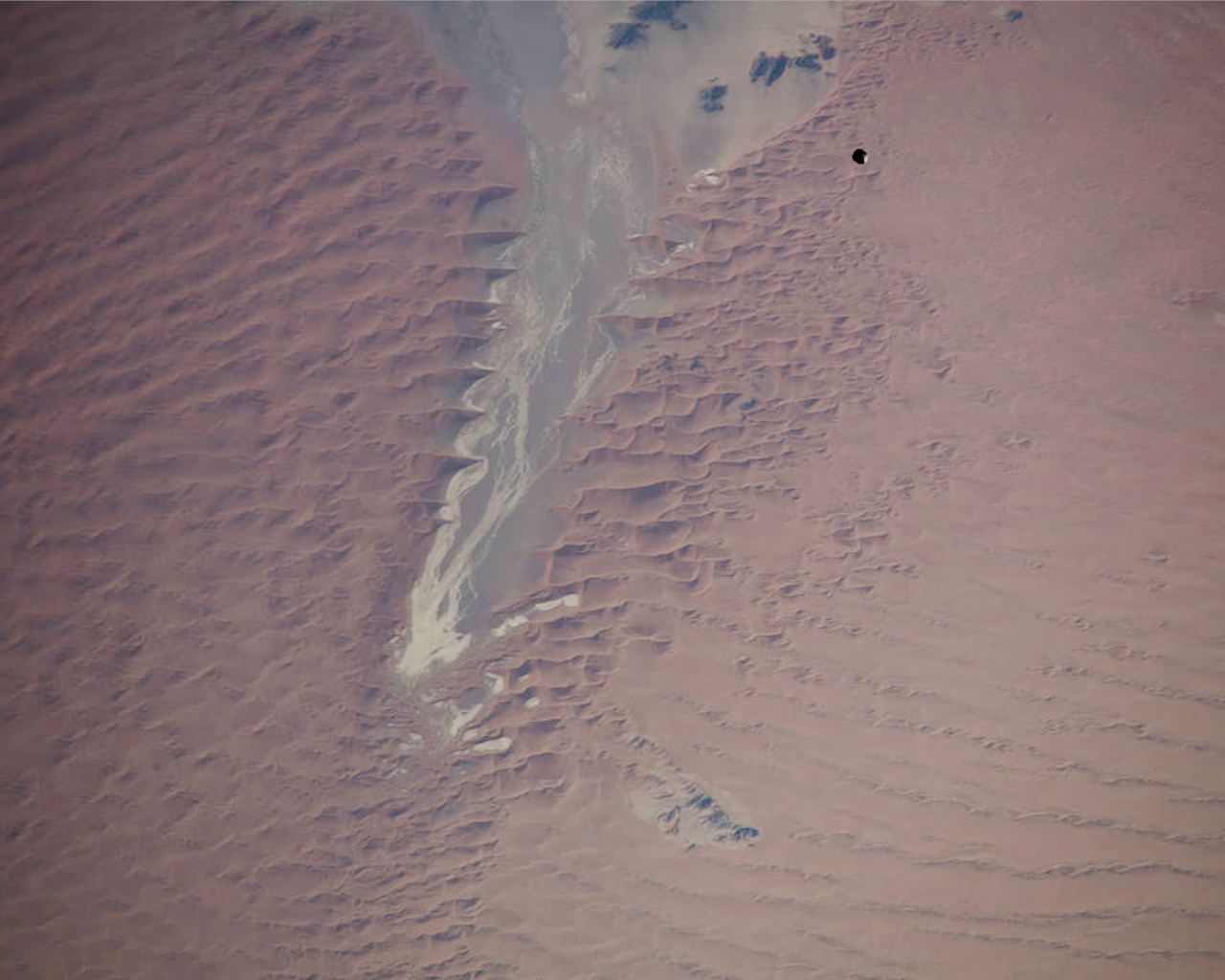 Satellite image of another spacecraft above a red, sandy landscape.