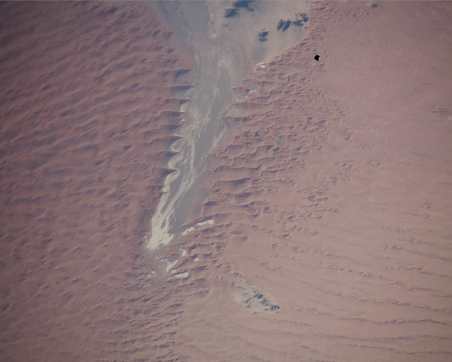 Satellite image of another spacecraft above a red, sandy landscape.