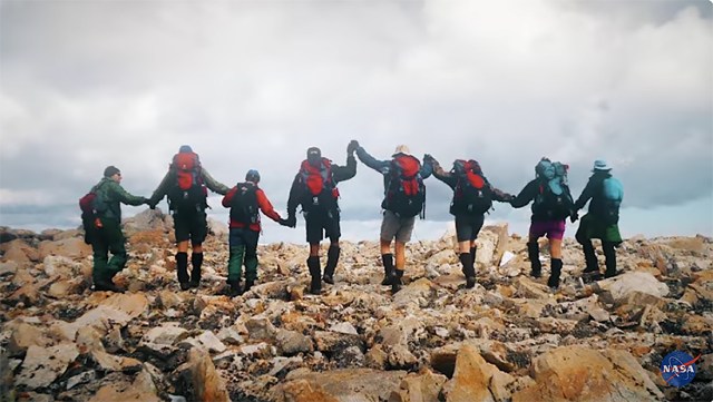 A group of people standing on rocks holding hands