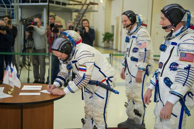 At the Gagarin Cosmonaut Training Center in Star City, Russia, Expedition 55 crew member Oleg Artemyev of Roscosmos (left) signs in Feb. 21 for the final day of crew qualification exams as crewmates Ricky Arnold of NASA (center) and Drew Feustel of NASA (right) look on. They will launch March 21 from the Baikonur Cosmodrome in Kazakhstan on the Soyuz MS-08 spacecraft for a five-month mission on the International Space Station.