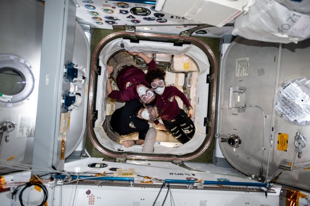 iss062e087445 (March 9, 2020) --- From top to bottom, Expedition 62 crewmembers Andrew Morgan, Oleg Skripochka and Jessica Meir are pictured inside the SpaceX Dragon resupply ship shortly after opening the hatch to the U.S. space freighter. The trio wore portable breathing gear during the initial entry and tested the spaceship's atmosphere for particles and airway irritants that may have dislodged during its launch and ascent to space.