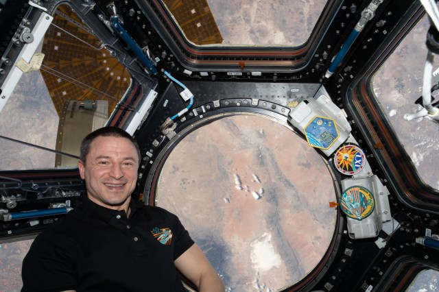 iss062e147795 (April 12, 2020) --- NASA astronaut and Expedition 62 Flight Engineer Andrew Morgan poses for a portrait inside the International Space Station's "window to the world," the cupola. The orbiting lab was flying above the state of New Mexico at the time this photograph was taken.
