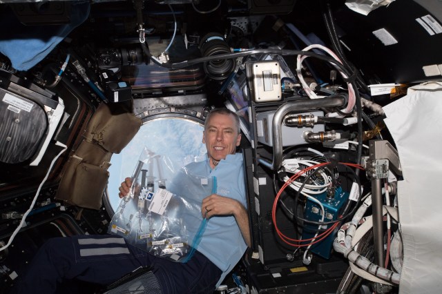 Flight Engineer Drew Feustel holds a bag containing samples that had been collected, documented and inspected for the Protein Crystal Growth-9 experiment. Feustel was in the Cupola as the International Space Station was orbiting over southern Mexico near the Guatemalan border.