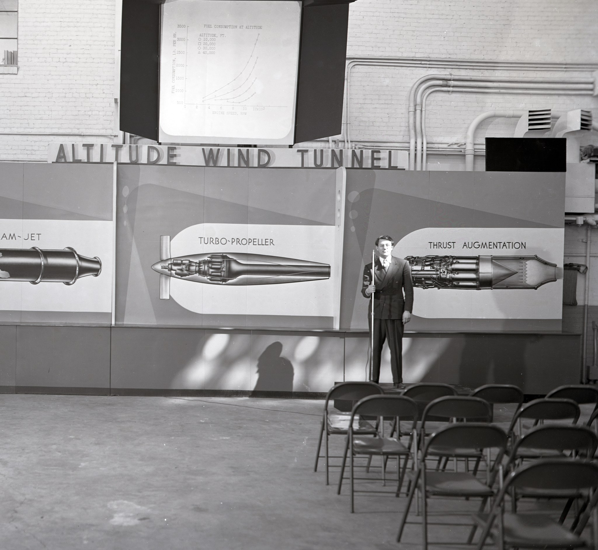 Man standing in front of sign in large room.