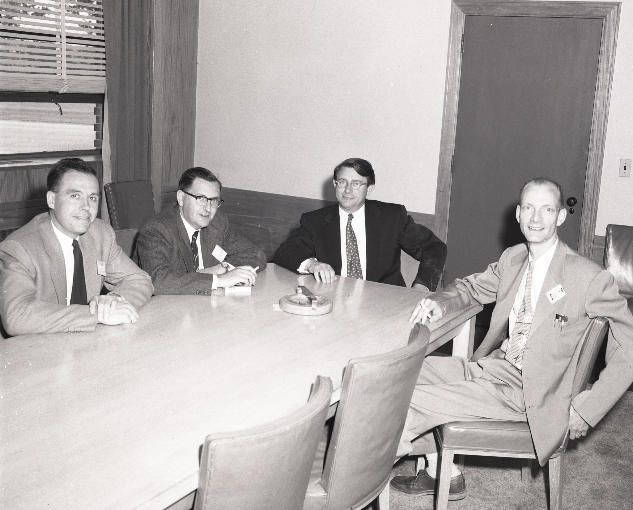 Four men seated at conference table.