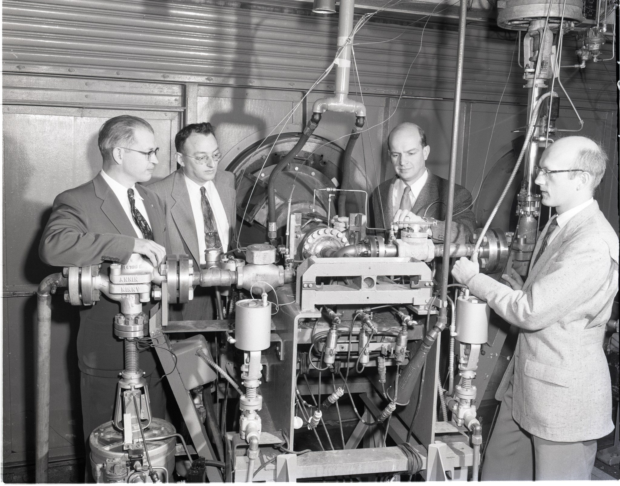 Four men looking at engine test stand.