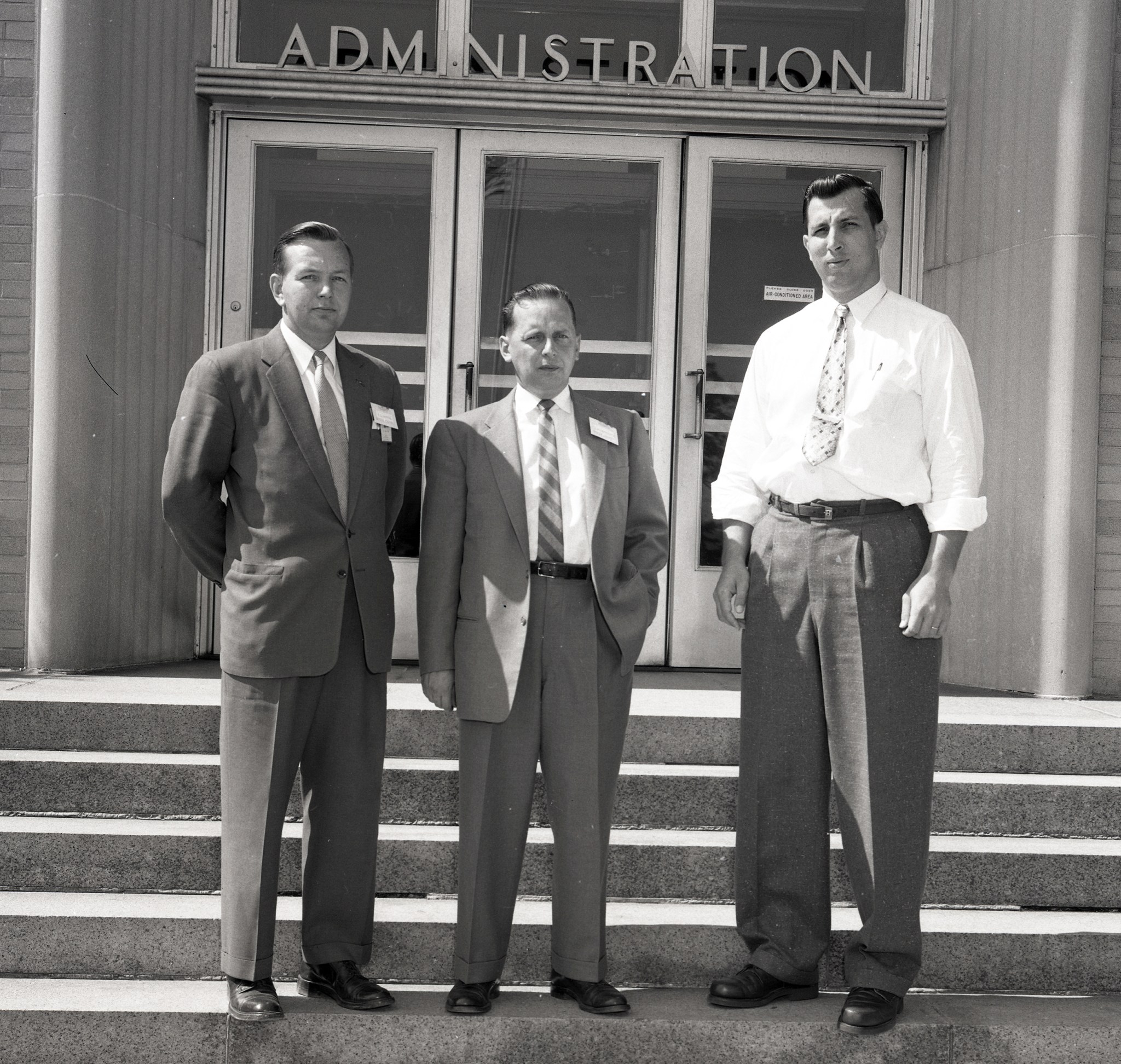 Three men standing in front of building.