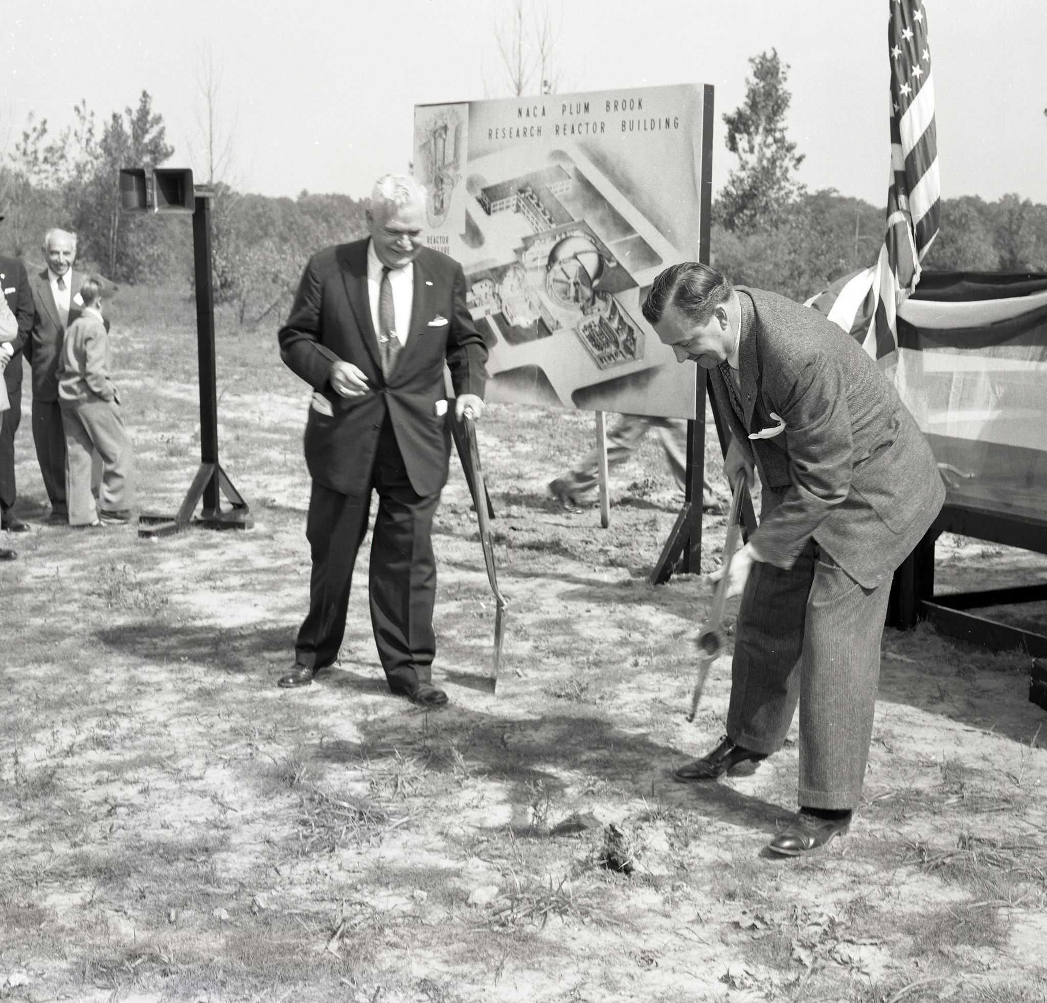 Two men digging earth at ceremony.