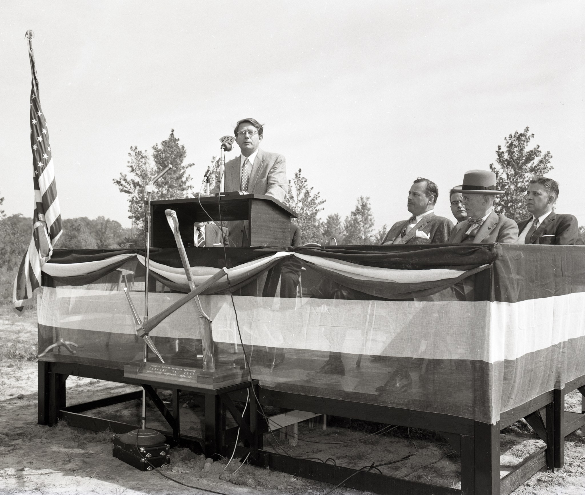 Man speaking at podium outdoors.