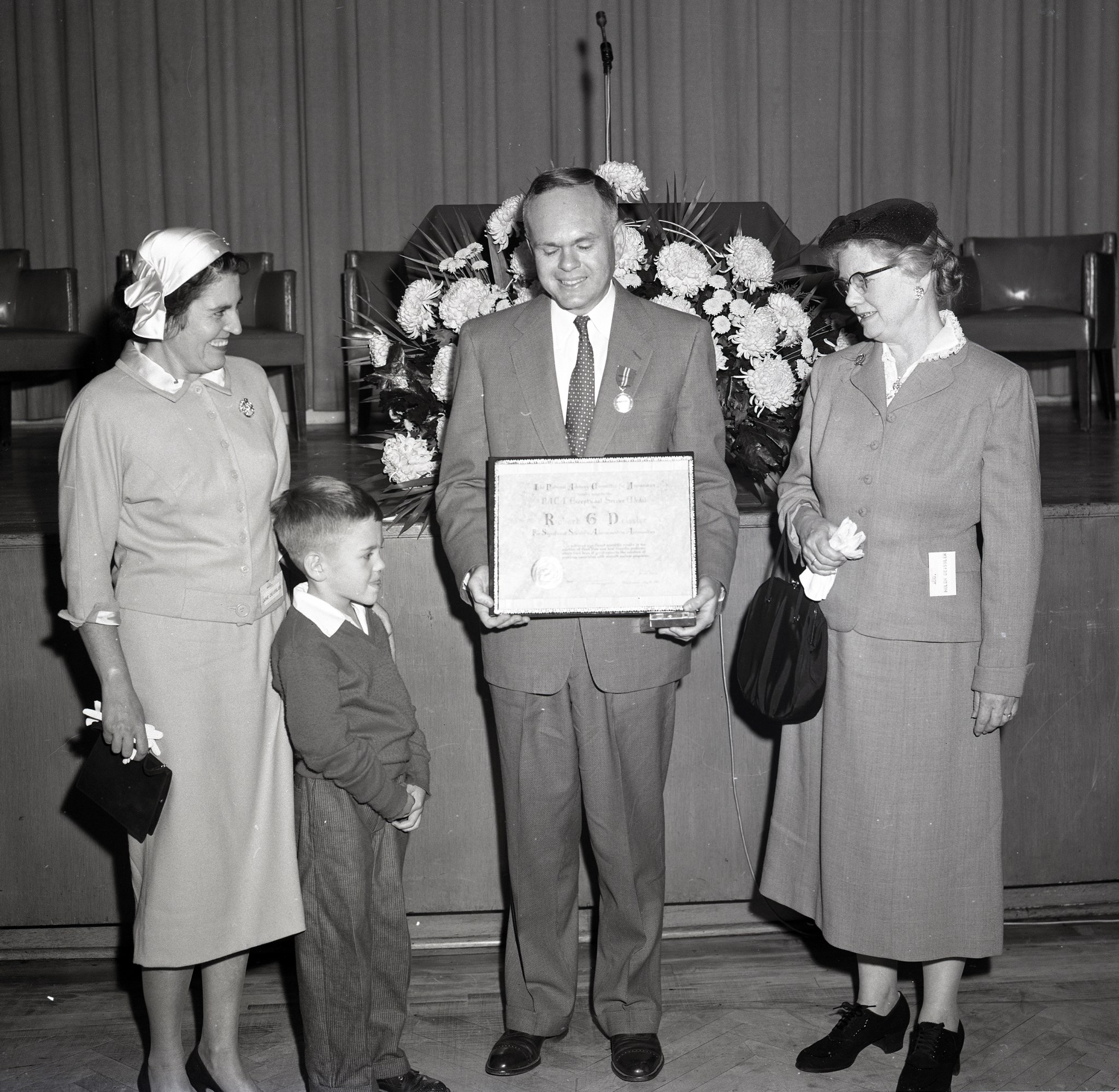 Man holding award with two women and a child.