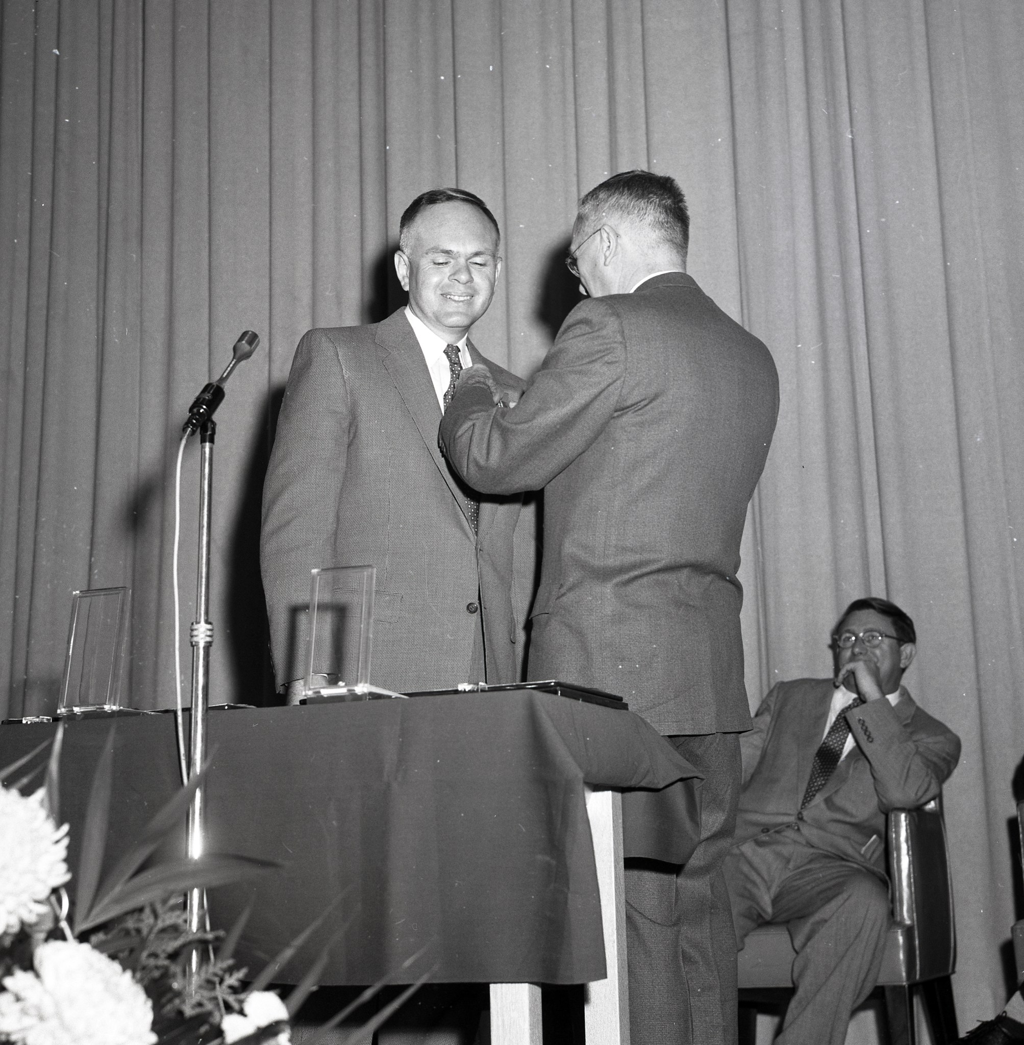 Man placing pin on other man.