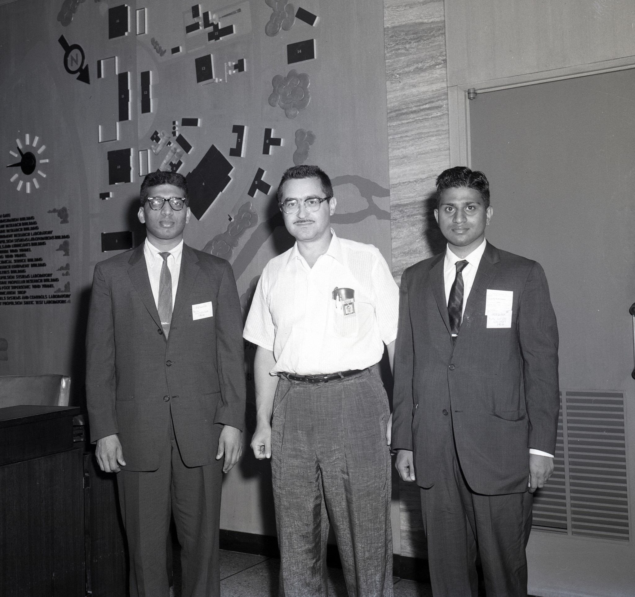 Three men standing in lobby.