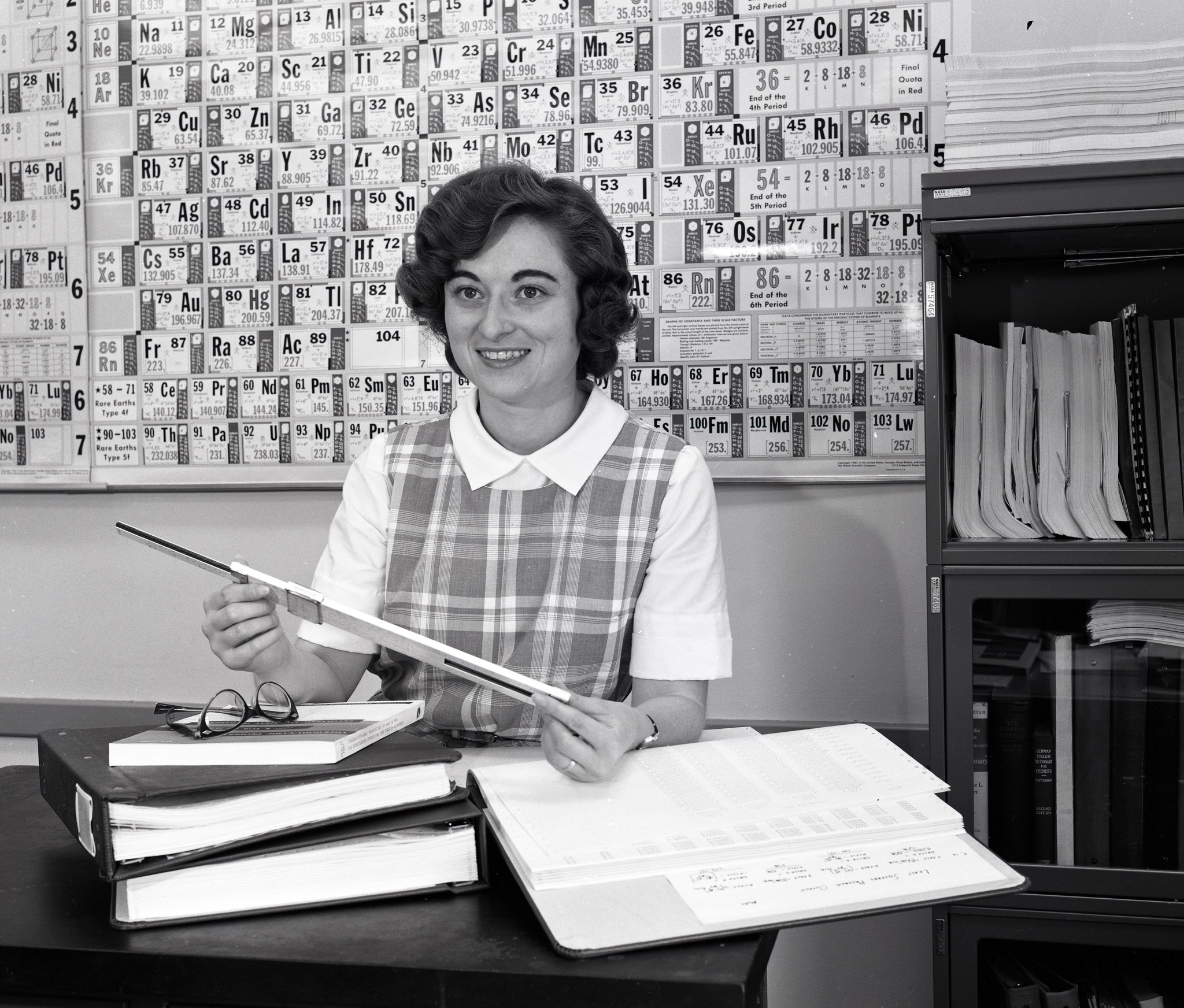 Woman at desk with slide rule.