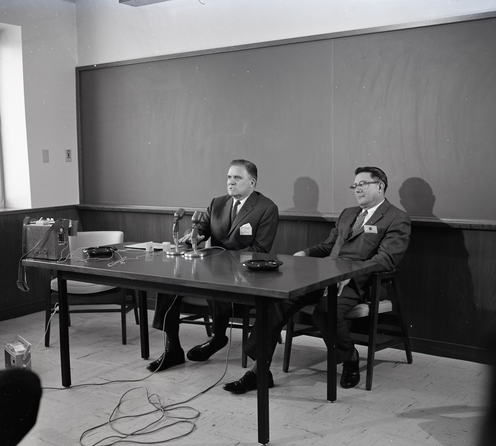 Two men seated at table in room.