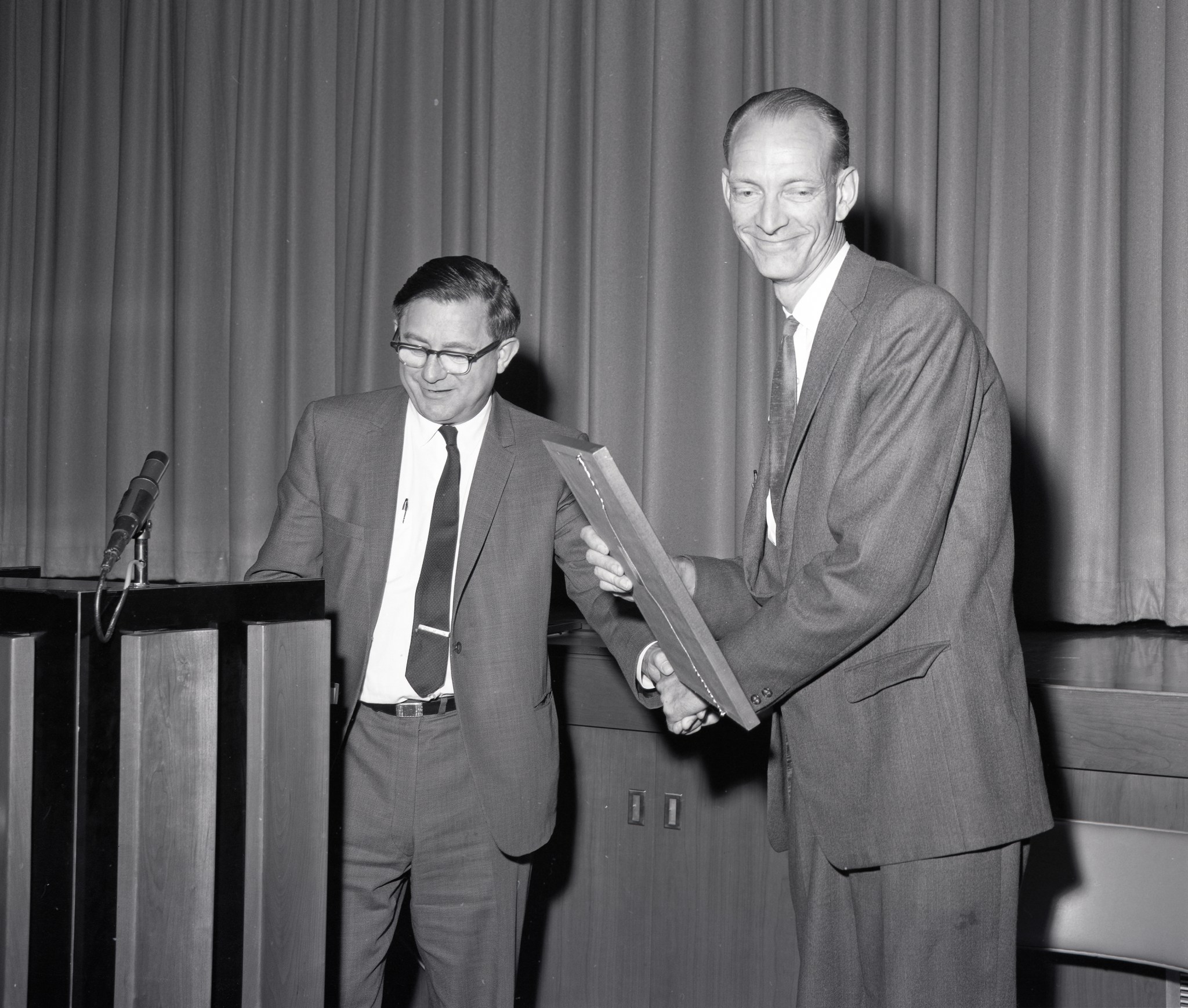 Man presenting award to another man.