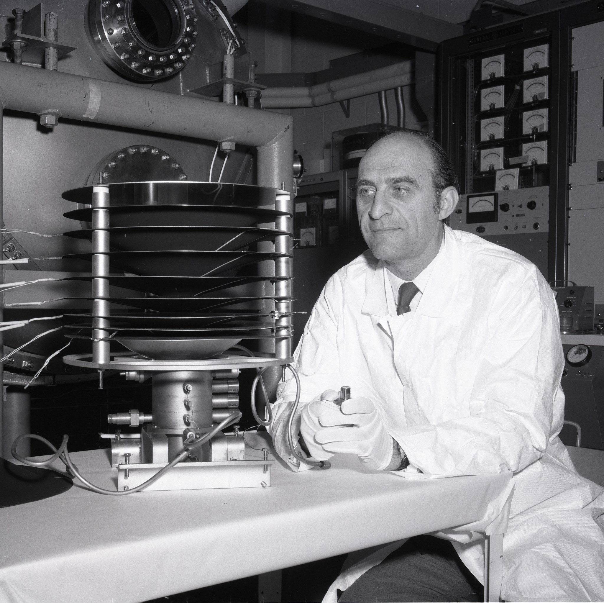 Man in lab coat viewing hardware.