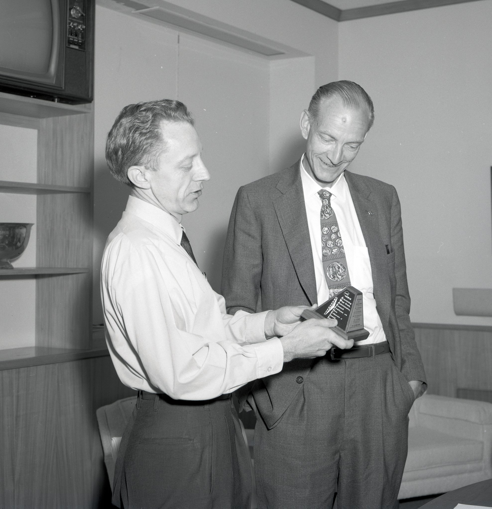 Two men examining award.