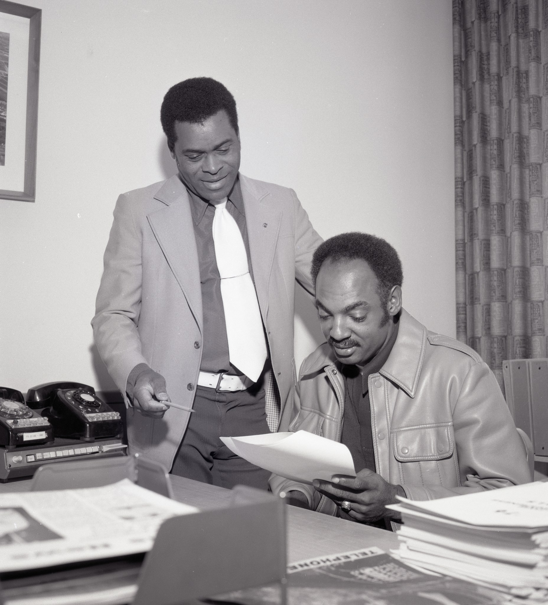 Two men at desk in office.