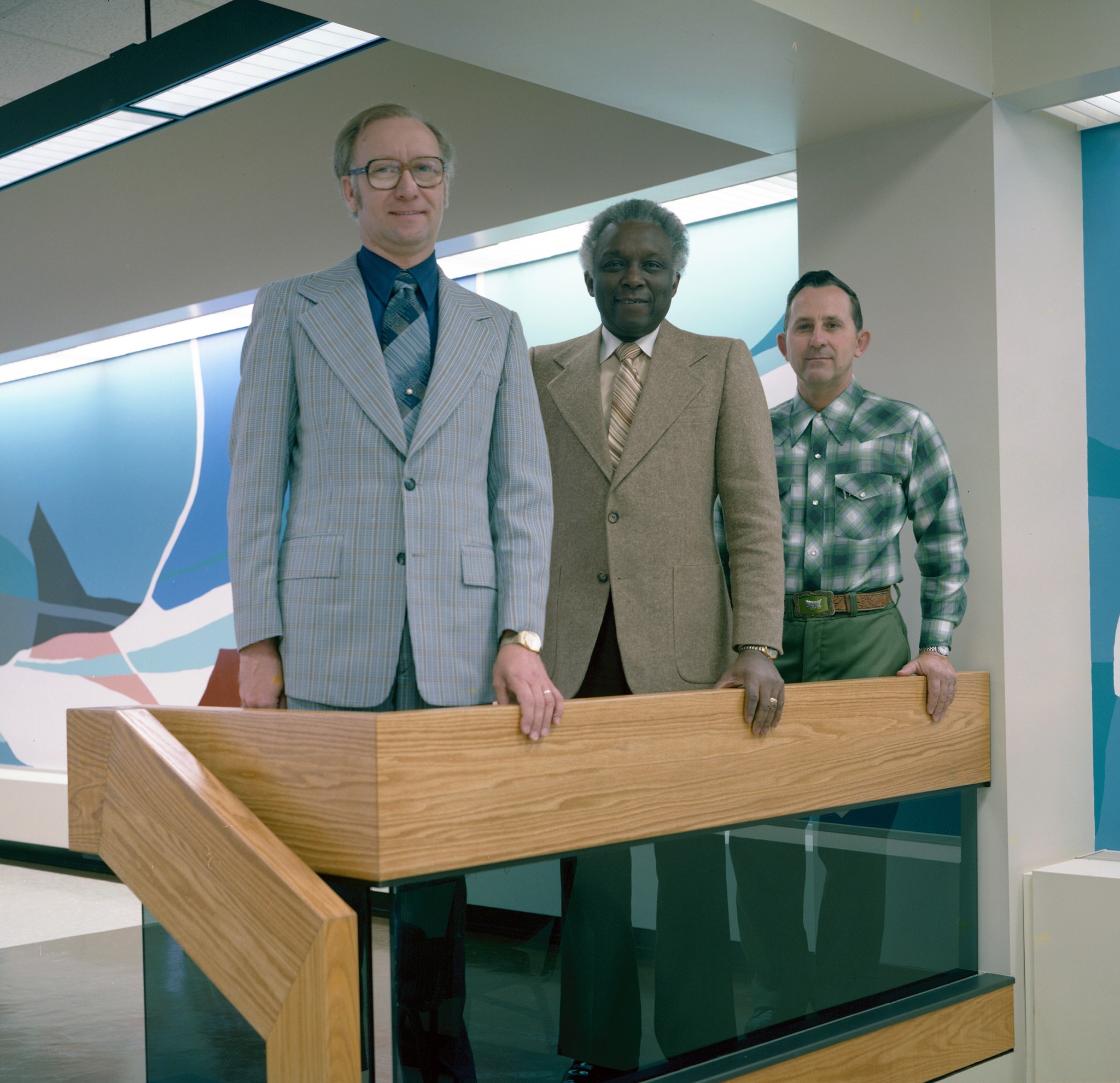 Three men standing at railing.