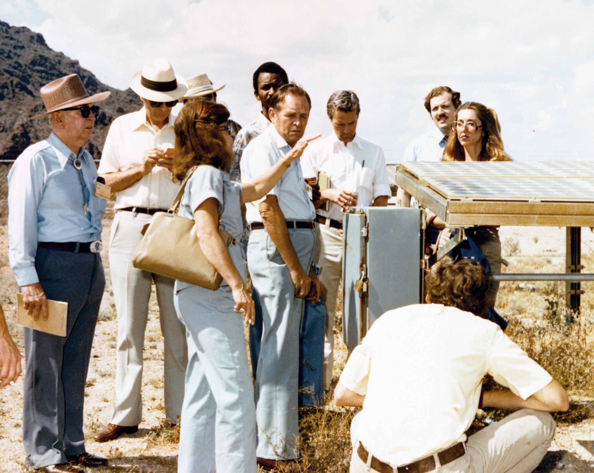 Group of people examining a solar array in desert.