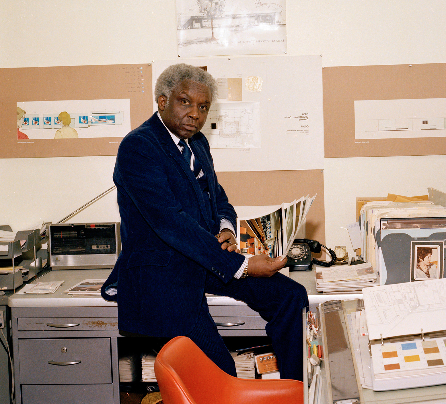 Man in office showing print photographs.