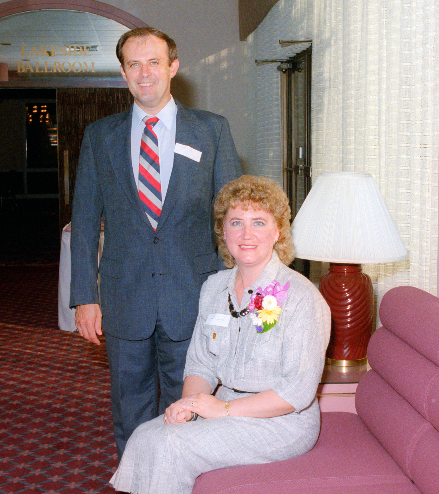 Man standing next to seated woman.