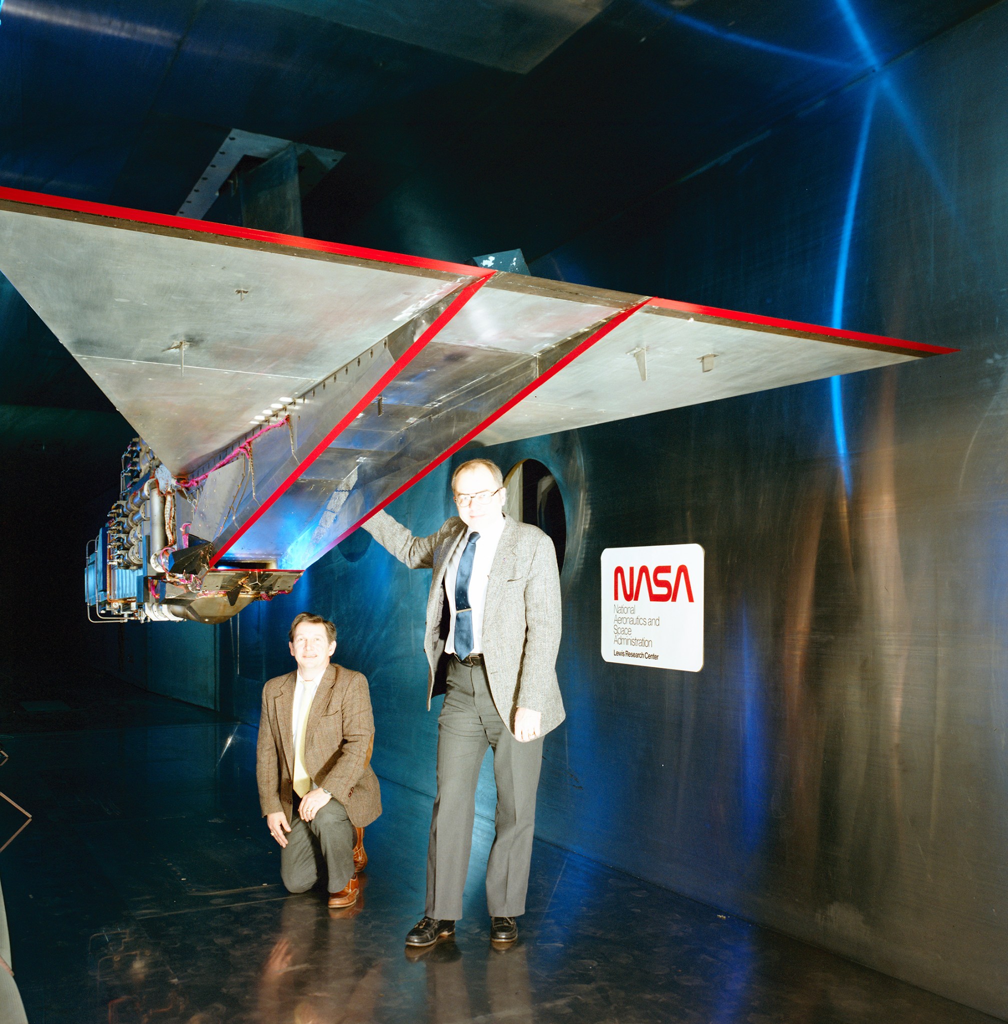 Two men looking inlet in wind tunnel.