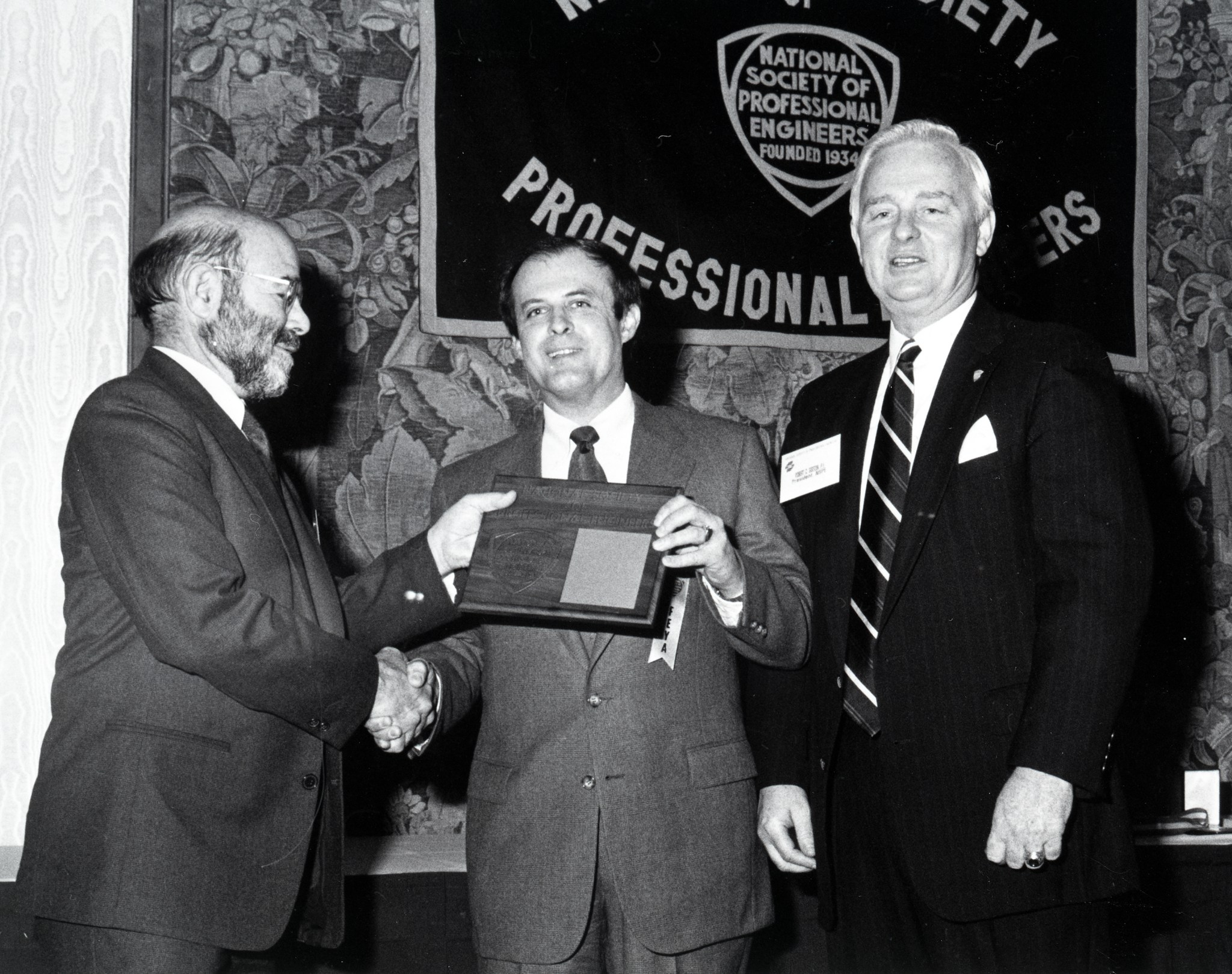 Three men standing with plaque.