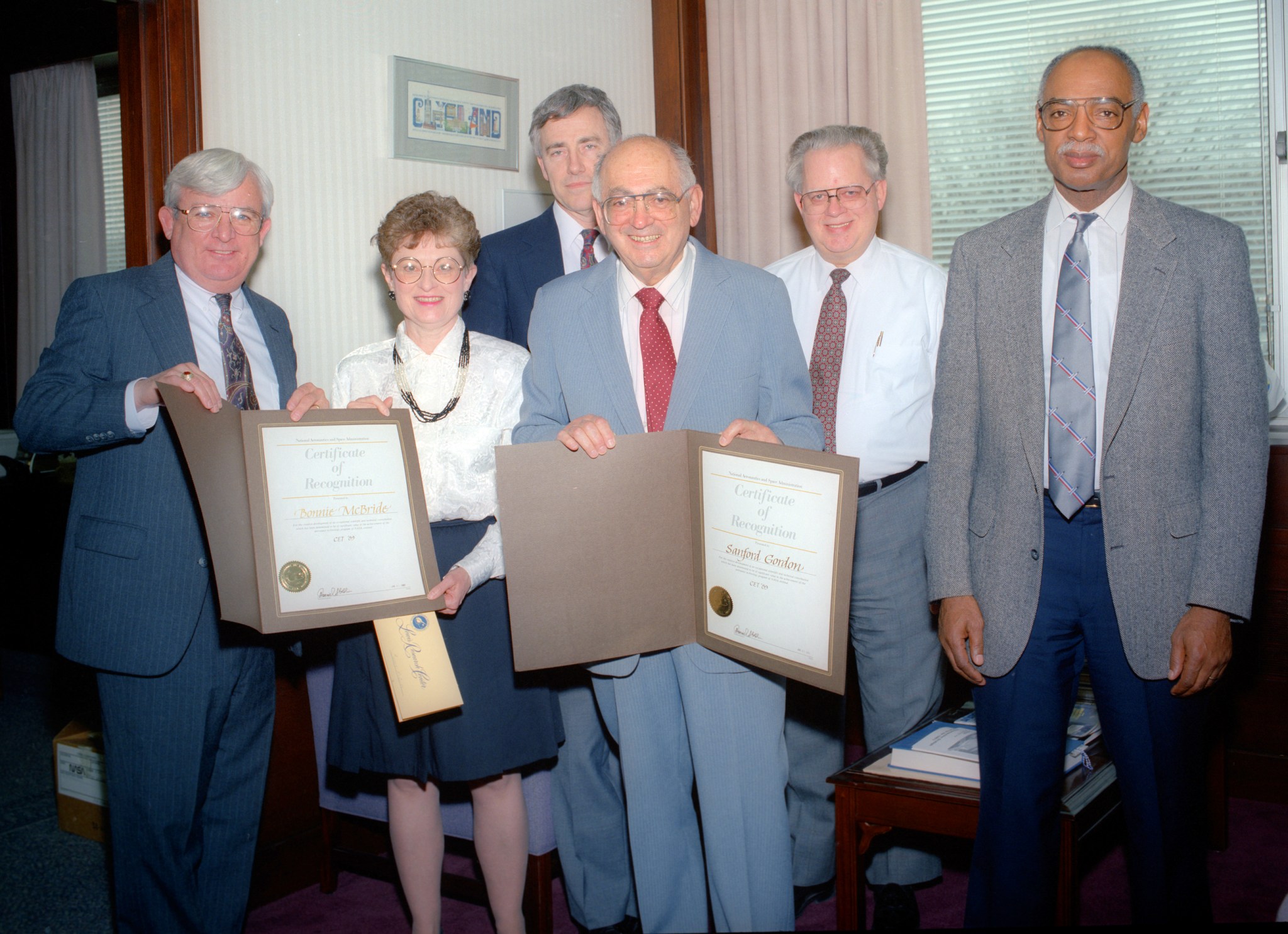 Group of people holding awards in office.