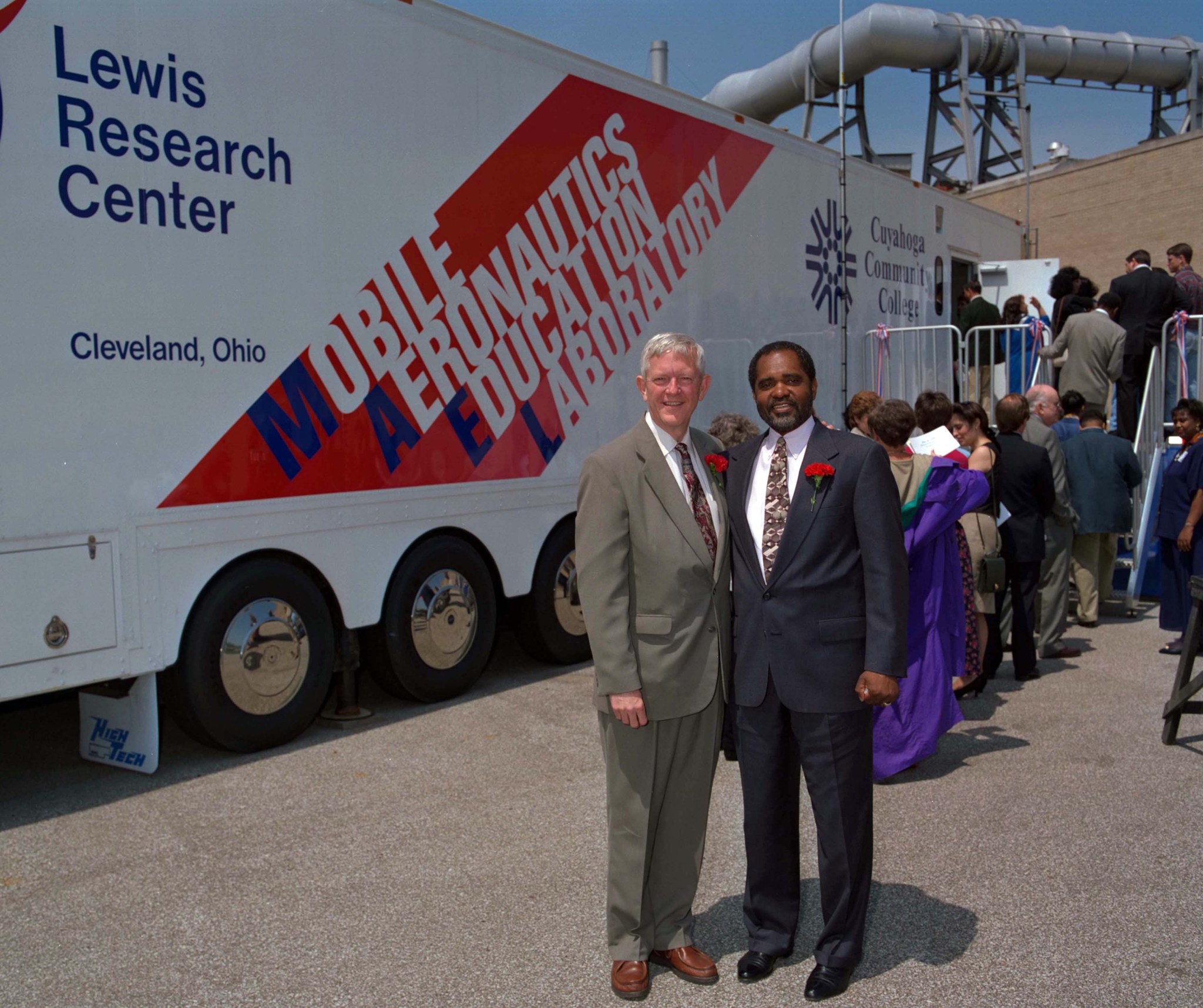 Two men standing outside educational trailer.