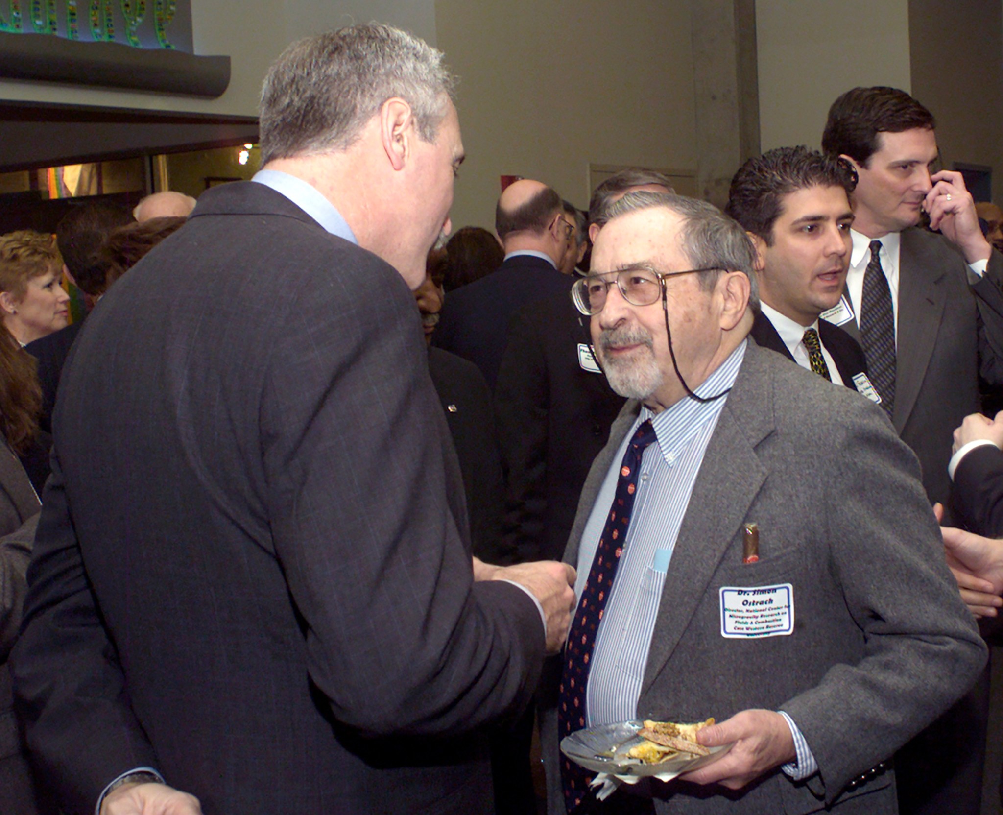 Two men talking in crowded room.