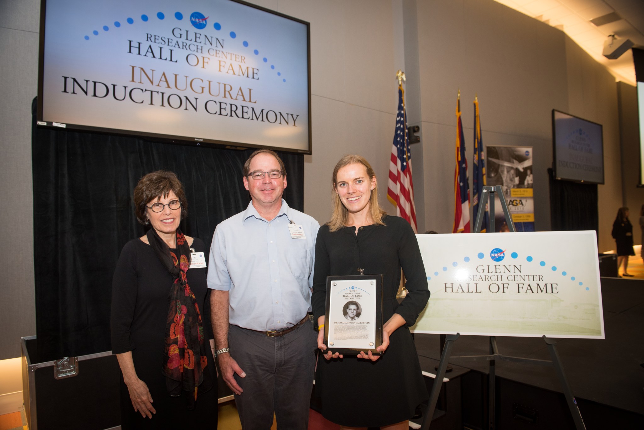 Two women and a man standing with plaque.