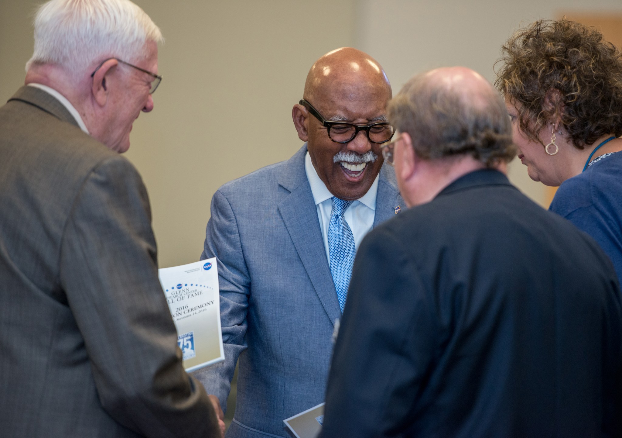 Man shakes hands with several others.