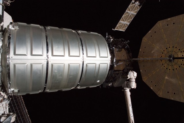 The Northrop Grumman (formerly Orbital ATK) Cygnus resupply ship with its round, brass-colored UltraFlex solar arrays is guided to its port on the Unity module shortly after it was captured with the Canadarm2 robotic arm.
