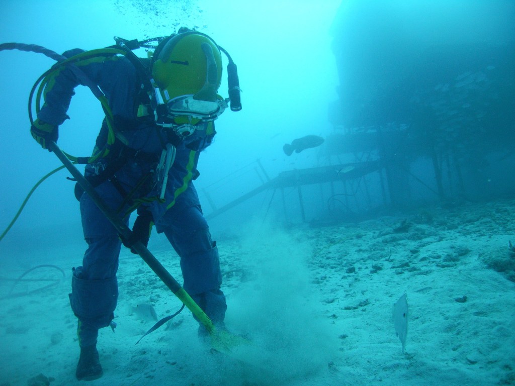 A diver uses a shovel on the bottom of a simulated ocean floor.