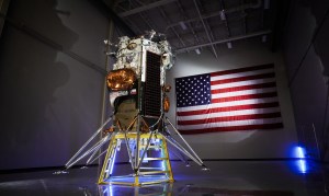 The Nova-C lunar lander sits in front of an American flag with dramatic lighting against it.