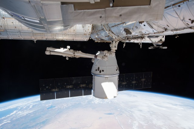The SpaceX Dragon resupply ship, held firmly in the grip of the Canadarm2 robotic arm, is pictured being remotely maneuvered very slowly by robotics engineers on the ground before it was installed to the Harmony module's Earth-facing port.