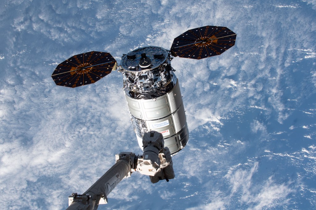 The Canadarm2 robotic arm reaches out toward Northrop Grumman's Cygnus space freighter, packed with more than 8,200 pounds of science experiments, crew supplies, and station hardware, for capture and installation to the International Space Station's Unity module. Both spacecraft were orbiting 262 miles above the Pacific Ocean off the coast of Japan's island of Hokkaido at the time of this photograph.