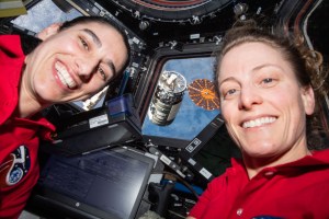 Expedition 70 Flight Engineers (from left) Jasmin Moghbeli and Loral O'Hara, both NASA astronauts, are pictured inside the cupola with Northrop Grumman's Cygnus resupply ship outside in the grips of the Canadarm2 robotic arm.