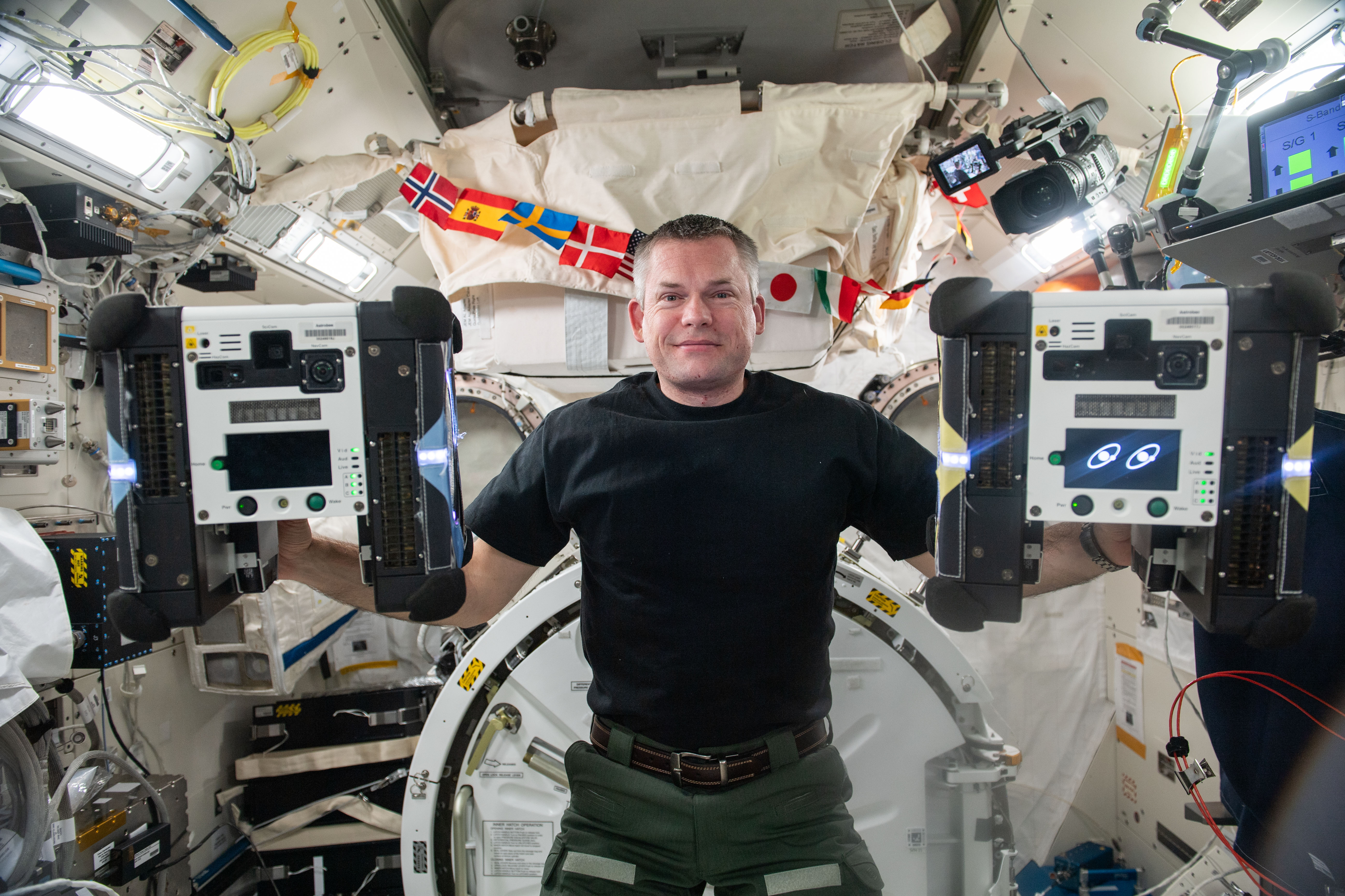 ESA (European Space Agency) astronaut and Expedition 70 Commander Andreas Mogensen shows off a pair of cube-shaped Astrobee robotic free flyers inside the International Space Station's Kibo laboratory module. The autonomous robots are powered by fans and vision-based navigation and are demonstrating their ability to assist astronauts with routine chores and provide remote monitoring abilities for mission controllers on the ground.