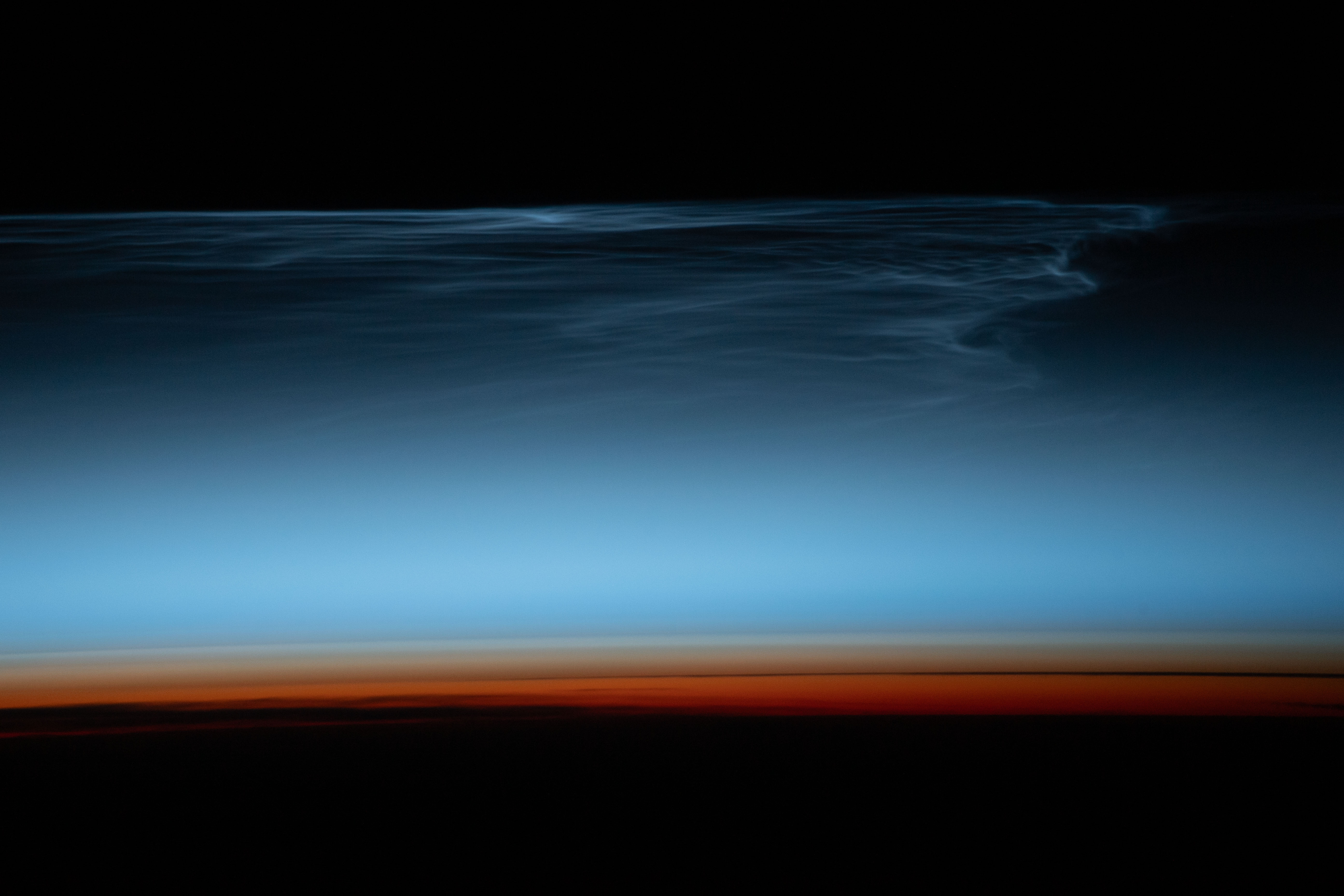 Noctilucent clouds, wispy clouds in Earth's upper atmosphere illuminated by the sunlight just after sunset, are pictured from the International Space Station as it orbited 269 miles above the south Pacific Ocean.