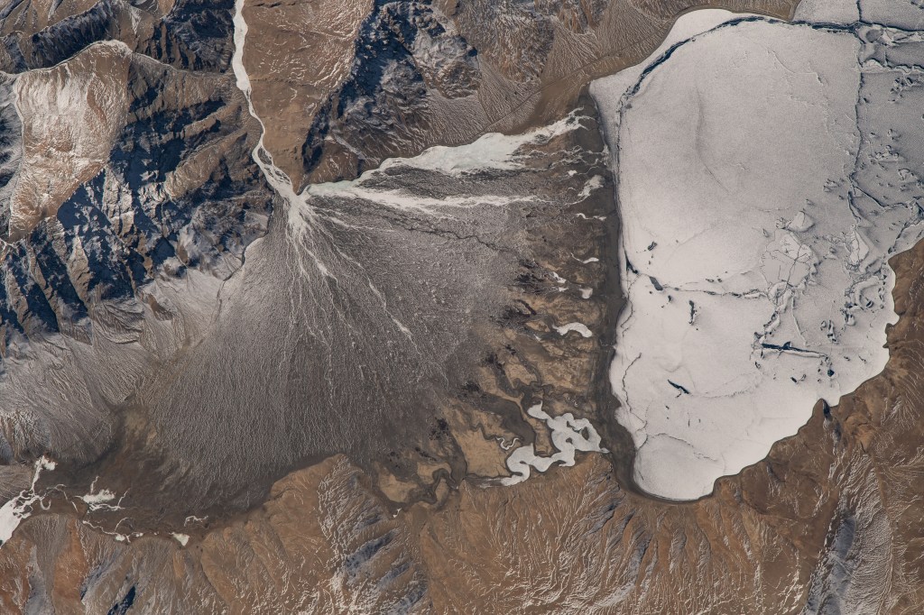 iss070e093443 (Feb. 15, 2024) -- An ice covered Lake Moriri (or Mountain Lake) sits in the high altitude of the Changtang Plateau in India. Next to it, snow drifts through mountain sides, feeding into the body of water, as the International Space Station orbited 260 miles above.