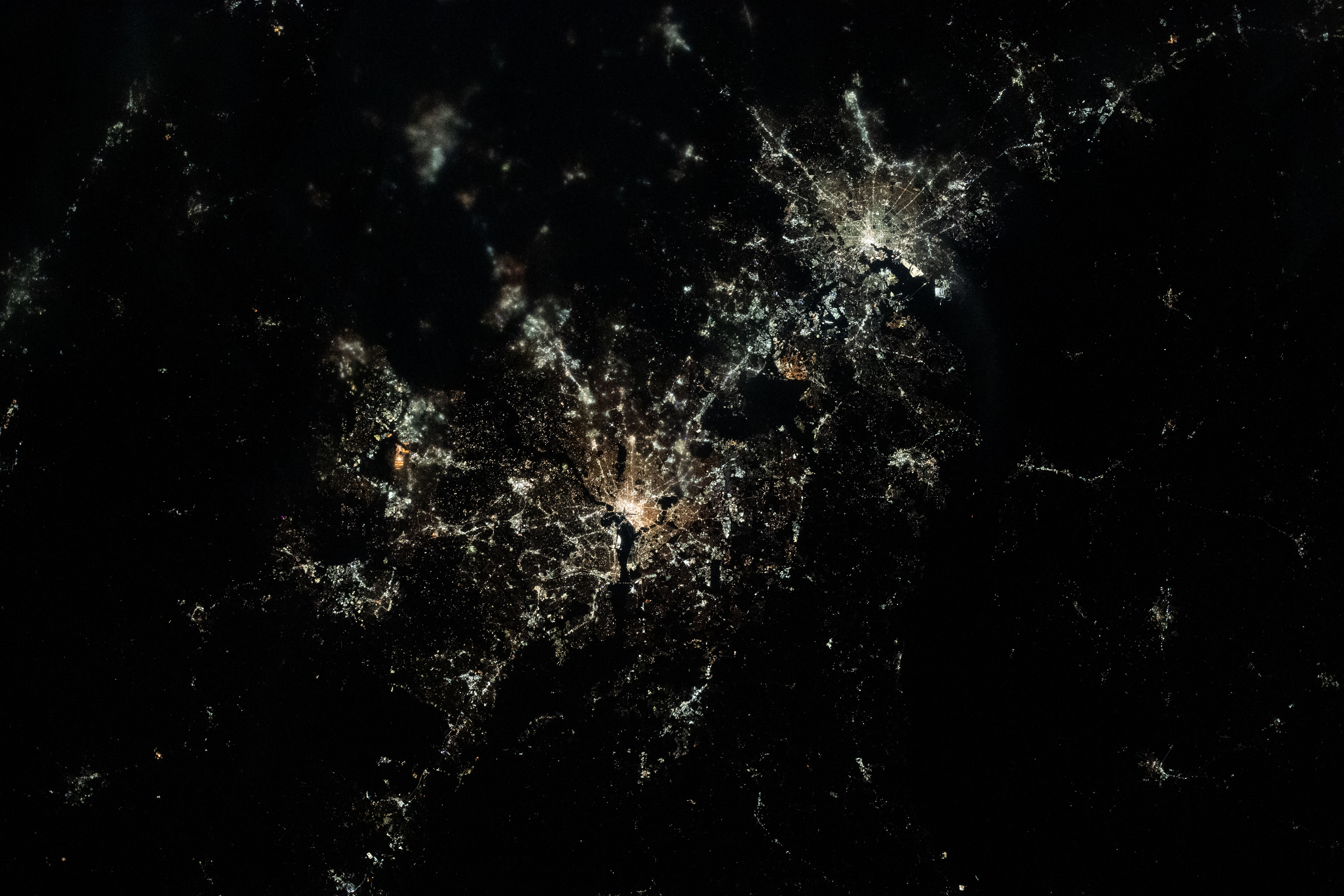 This nighttime, near overhead view shows Washington, D.C. (center) and Baltimore, Maryland (upper right) on Chesapeake Bay. Expedition 70 Flight Engineer Loral O'Hara of NASA photographed the area as the International Space Station orbited 261 miles above.