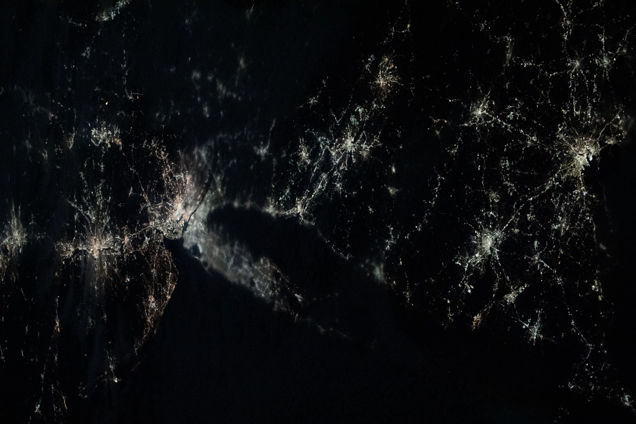 This nightime view shows major northeastern U.S. urban centers including a cloudy New York City; Philadelphia, Pennsylvania; Providence, Rhode Island; Boston Massachussetts; and more. Expedition 70 Flight Engineer Loral O'Hara of NASA photographed the area as the International Space Station orbited 262 miles above the Gulf of Maine.