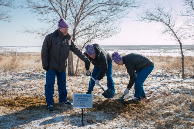 At the Cosmonaut Hotel crew quarters in Baikonur, Kazakhstan, Expedition 55 crewmember Ricky Arnold of NASA (center) plants a tree in his name March 15 in traditional pre-launch activities. Assisting him are his crewmates, Oleg Artemyev of Roscosmos (left) and Drew Feustel of NASA (right). They will launch March 21 on the Soyuz MS-08 spacecraft from the Baikonur Cosmodrome on a five-month mission to the International Space Station.