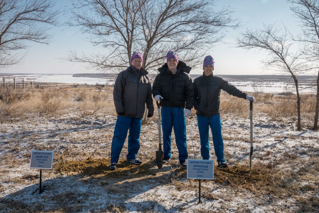 At the Cosmonaut Hotel crew quarters in Baikonur, Kazakhstan, Expedition 55 crew members Oleg Artemyev of Roscosmos (left), Ricky Arnold of NASA (center) and Drew Feustel of NASA (right) pose for pictures March 15 after Arnold planted a tree in his name in traditional pre-launch activities. They will launch March 21 on the Soyuz MS-08 spacecraft from the Baikonur Cosmodrome on a five-month mission to the International Space Station.