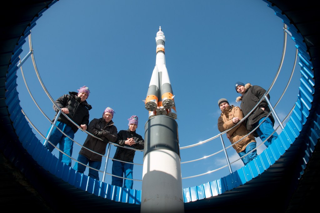 jsc2018e025544 - At the Cosmonaut Hotel crew quarters in Baikonur, Kazakhstan, the Expedition 55 prime and backup crew members pose for pictures by a Soyuz model March 15 as part of their pre-launch activities. From left to right are prime crewmembers Ricky Arnold of NASA, Oleg Artemyev of Roscosmos and Drew Feustel of NASA and backup crewmembers Alexey Ovchinin of Roscosmos and Nick Hague of NASA. Arnold, Artemyev and Feustel will launch March 21 on the Soyuz MS-08 spacecraft from the Baikonur Cosmodrome on a five-month mission to the International Space Station.