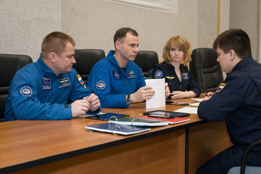 At the Cosmonaut Hotel crew quarters in Baikonur, Kazakhstan, Expedition 55 backup crew members Alexey Ovchinin of Roscosmos (left) and Nick Hague of NASA (center) listen to training instructors March 15 as part of their pre-launch activities. They are serving as backups to the prime crewmembers, Drew Feustel and Ricky Arnold of NASA and Oleg Artemyev of Roscosmos, who will launch March 21 on the Soyuz MS-08 spacecraft from the Baikonur Cosmodrome on a five-month mission to the International Space Station.