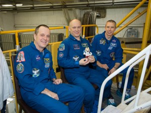At the Baikonur Cosmodrome in Kazakhstan, Expedition 55 crew member Oleg Artemyev of Roscosmos (center) holds a toy bear March 16 during Soyuz final fit check activities. The toy is one of several “zero gravity” mascots that will hang over the crew’s heads in the Soyuz during the vehicle’s ascent to orbit. Flanking Artemyev are his crewmates, Ricky Arnold of NASA (left) and Drew Feustel of NASA (right), who will launch March 21 on the Soyuz MS-08 spacecraft for a five-month mission on the International Space Station.